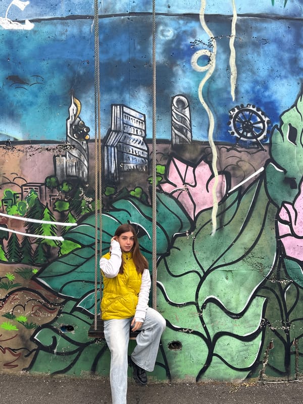 Woman poses against graffiti mural in Mnatobi, Georgia