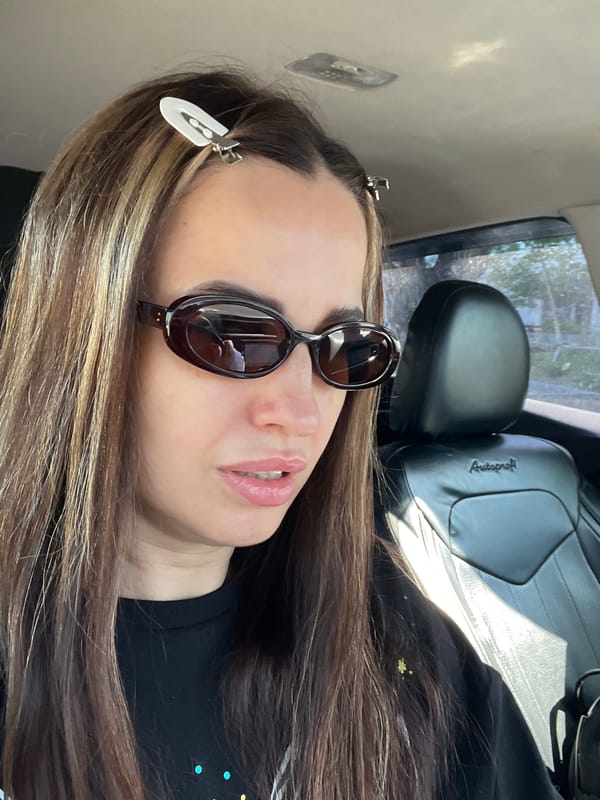 Woman takes car selfies wearing sunglasses and black shirt