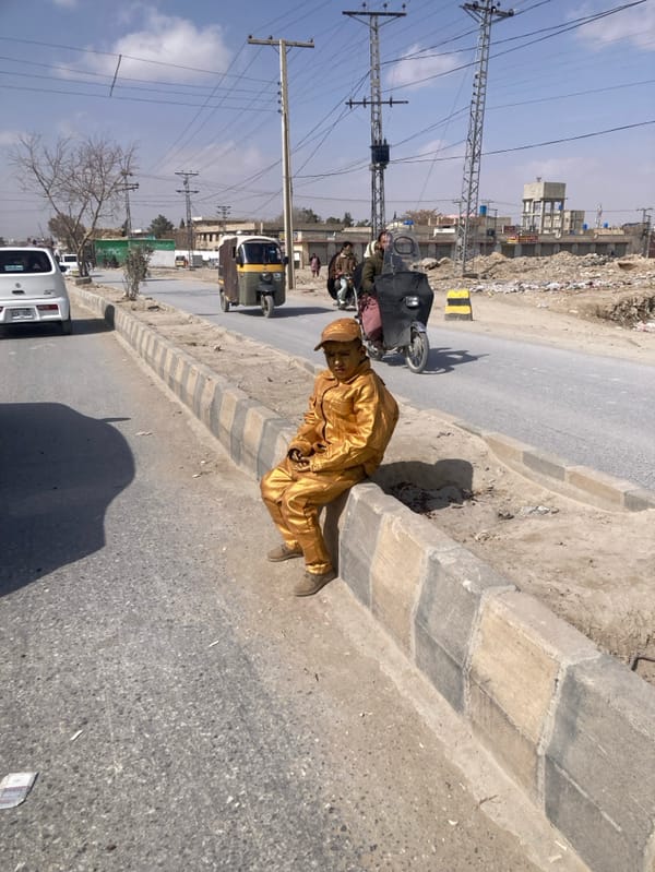 Man in gold suit sits roadside in Quetta