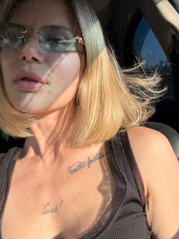 Tattooed blonde woman photographed in car, indoors in Mayma
