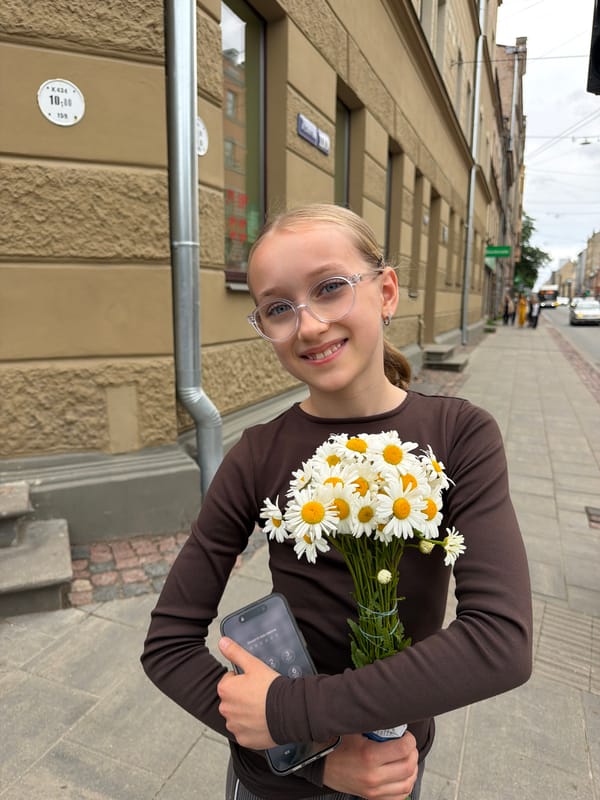 Girl with daisy bouquet photographed on Riga sidewalk