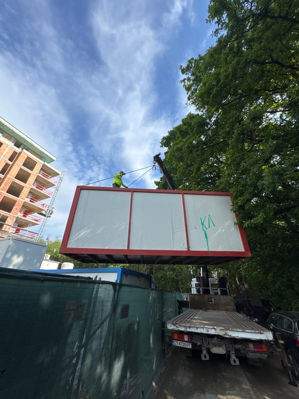 Crane lifts worker with container at construction site