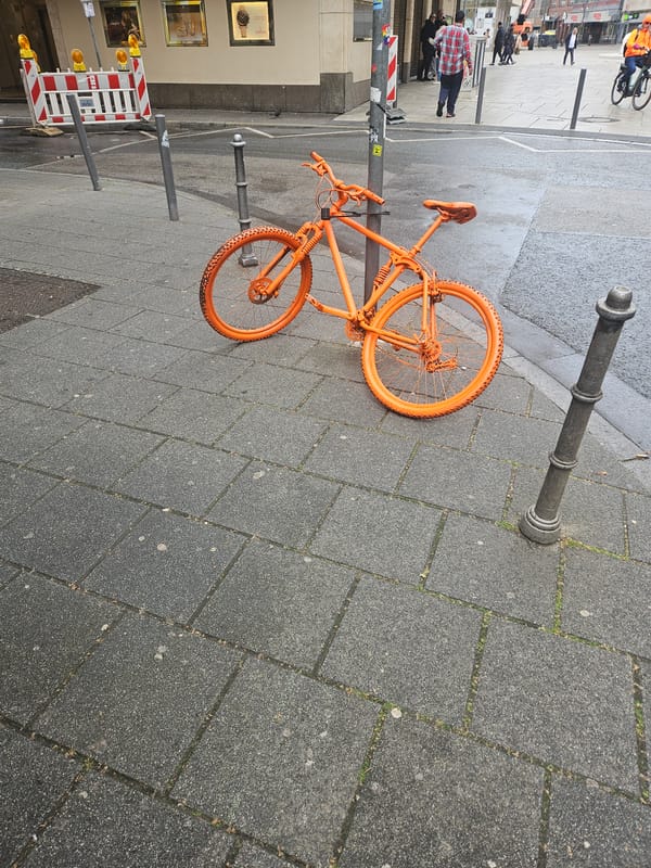 Orange bicycle spotted locked to bollard in Frankfurt