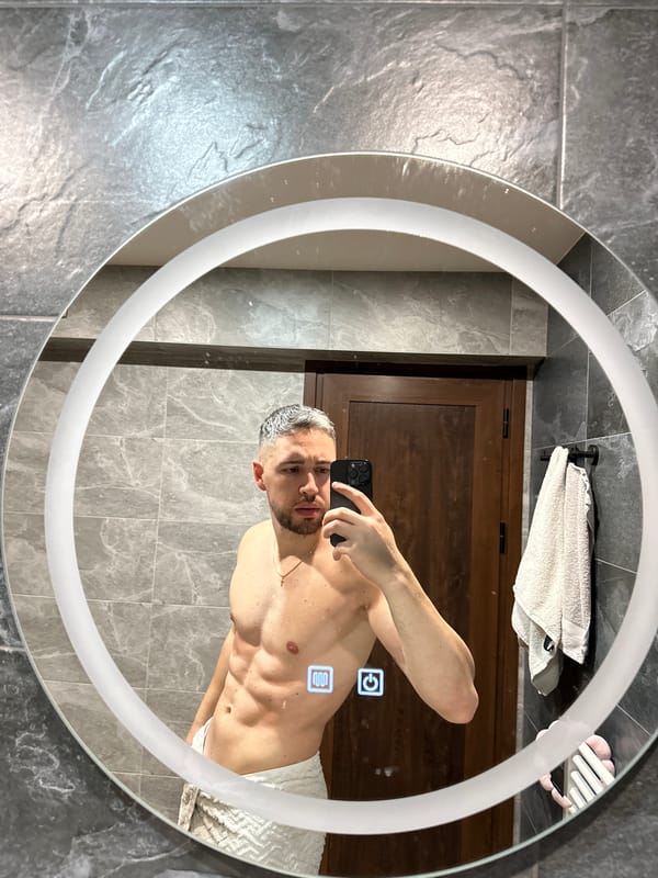Man Takes Bathroom Mirror Selfie in Gray Tiled Modern Bathroom