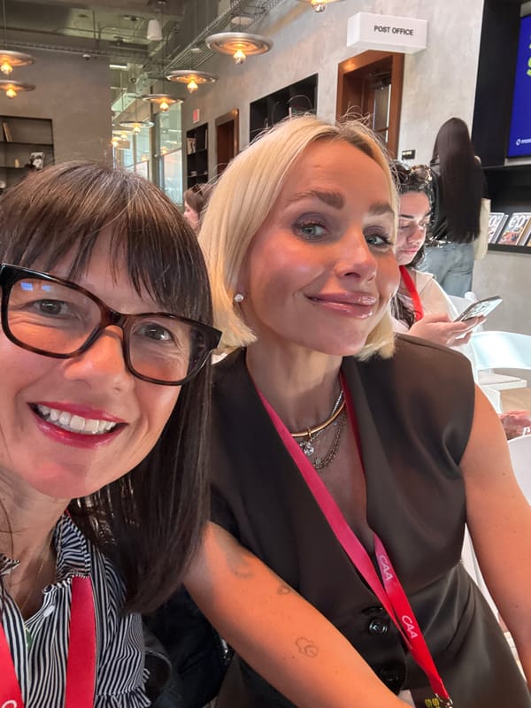 Two women take smiling selfie indoors
