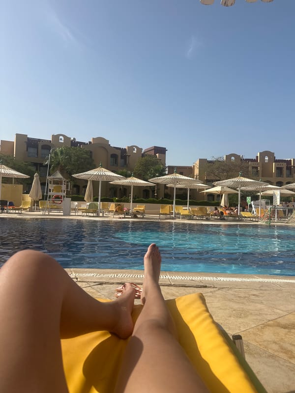 Person relaxes on yellow lounge chair by resort pool