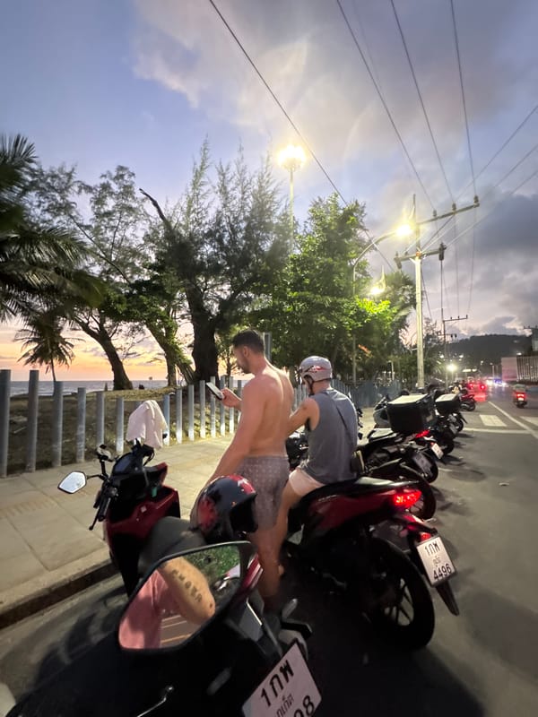 Sunset crowd gathers at Karon Beach, parasailor overhead