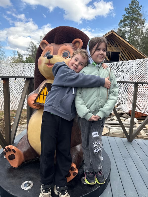 Children play on bear statue near A-frame cabin in Divnogorsk