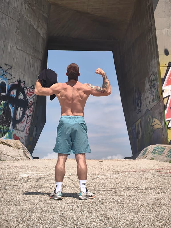 Man poses shirtless under concrete structure in Varna