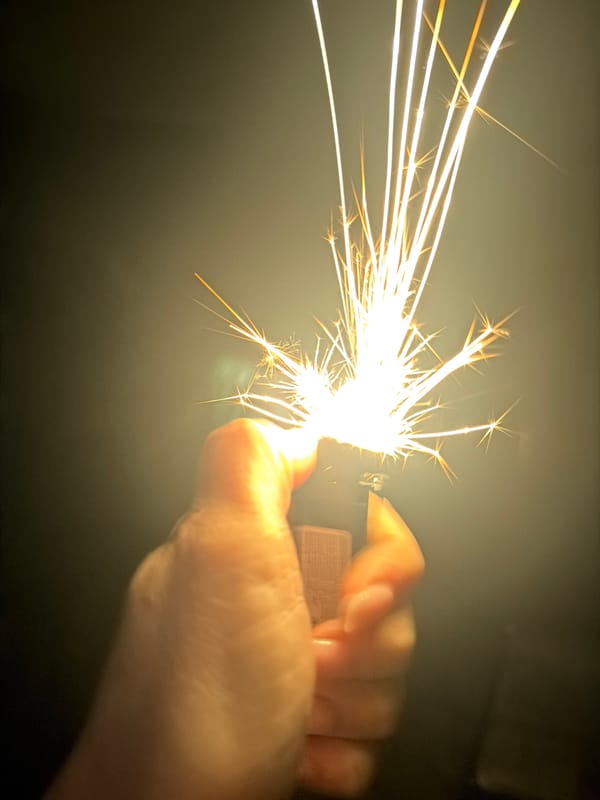 Hand holds sparking lighter in dark setting