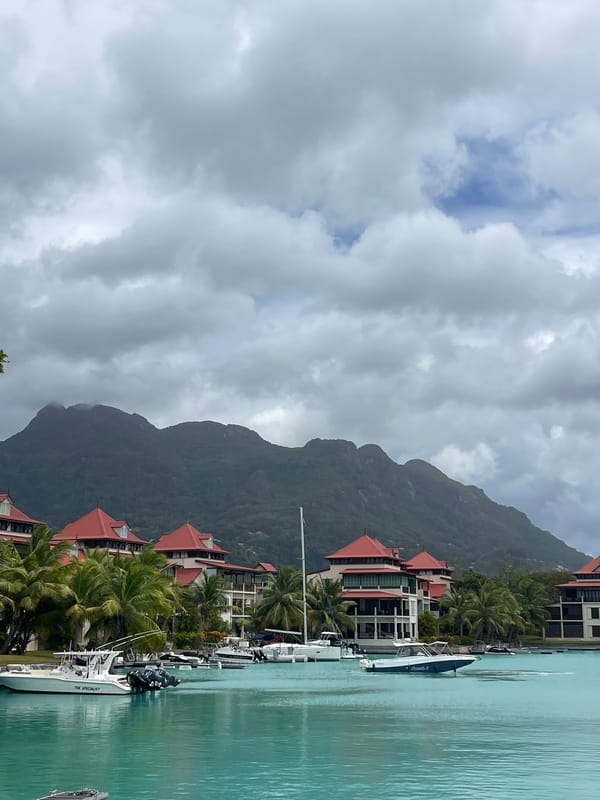 Calm Seychelles bay with red-roofed buildings and moored boats