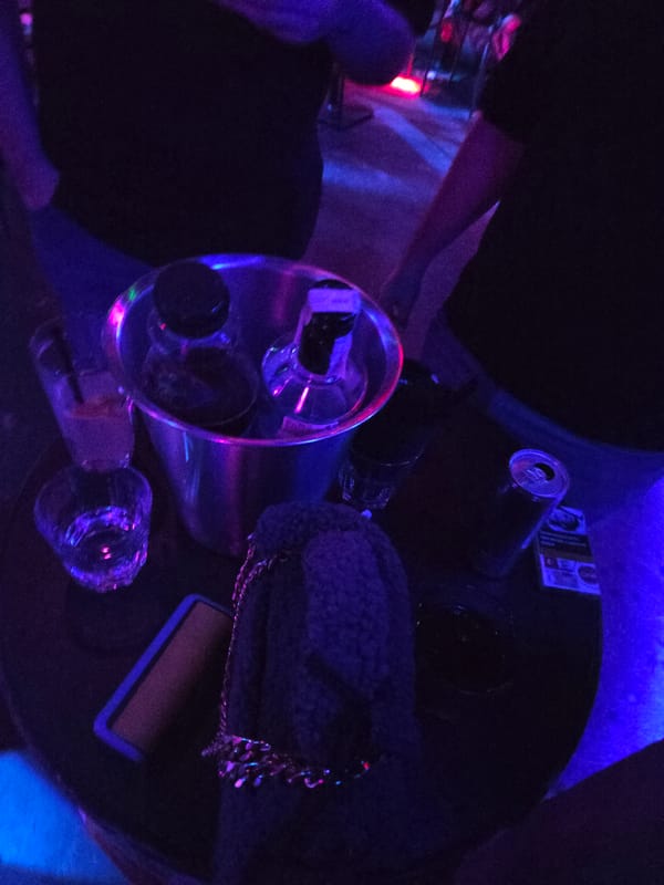 Dimly lit table with glasses and beverage documented