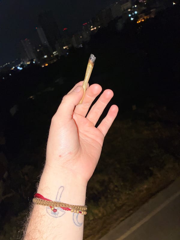 Person smokes marijuana overlooking foggy Huixquilucan skyline at night