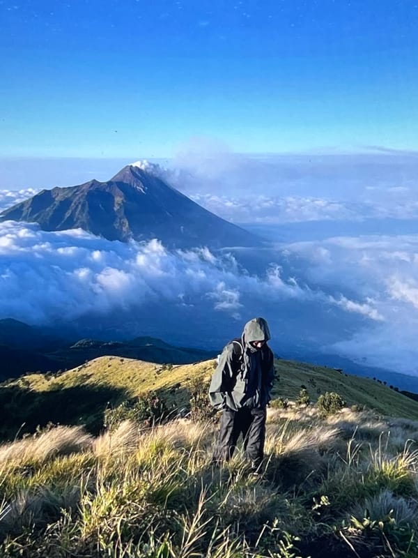 Hiker observed on mountain overlook viewing cloud-covered peaks
