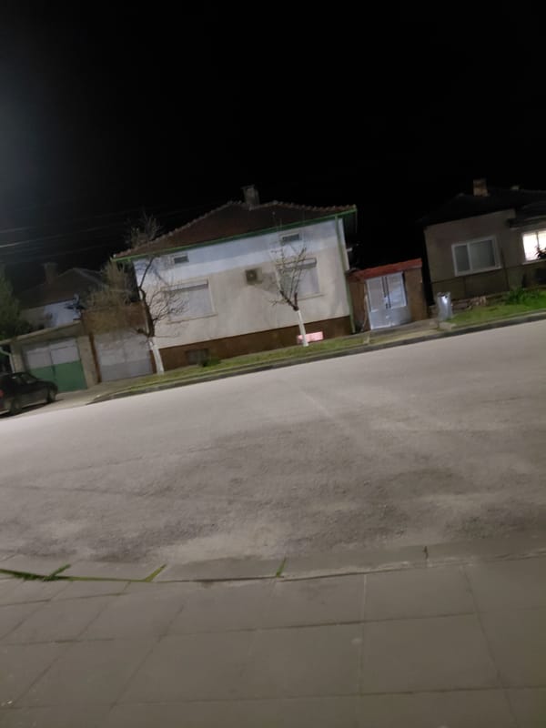 Nighttime urban street scene with lit residential buildings observed