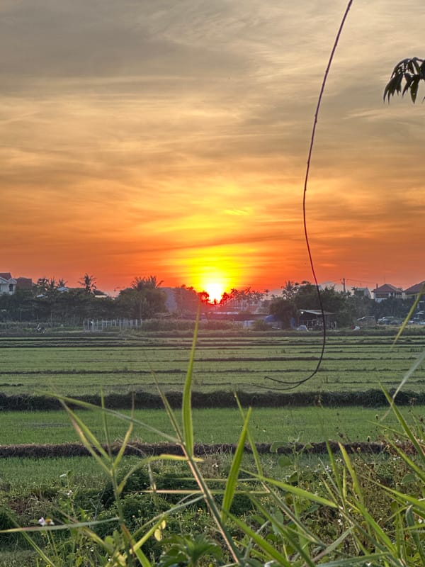 Sunset over Da Nang's rural outskirts, warm skies and distant hills