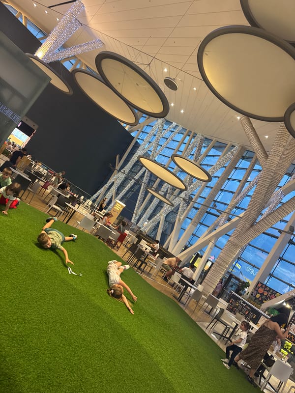 Children play on artificial turf in mall food court