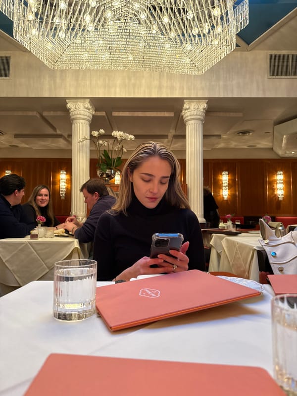 Woman checks phone at restaurant table in New York