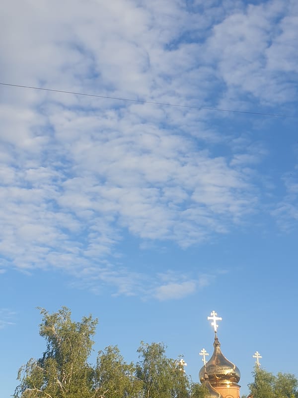 Golden Orthodox church dome glinting above the trees in Obukhiv