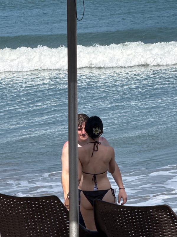 Kuta Beach on a busy day with surfers, a swim ban, and beachgoers