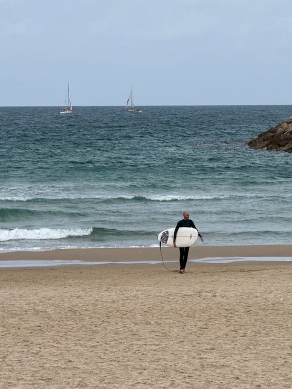 Surfer walks beach with white board in Herzliya