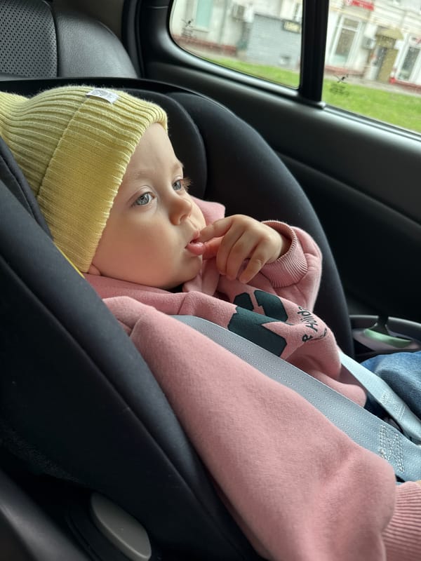 Baby in yellow hat observed in car seat in Moscow