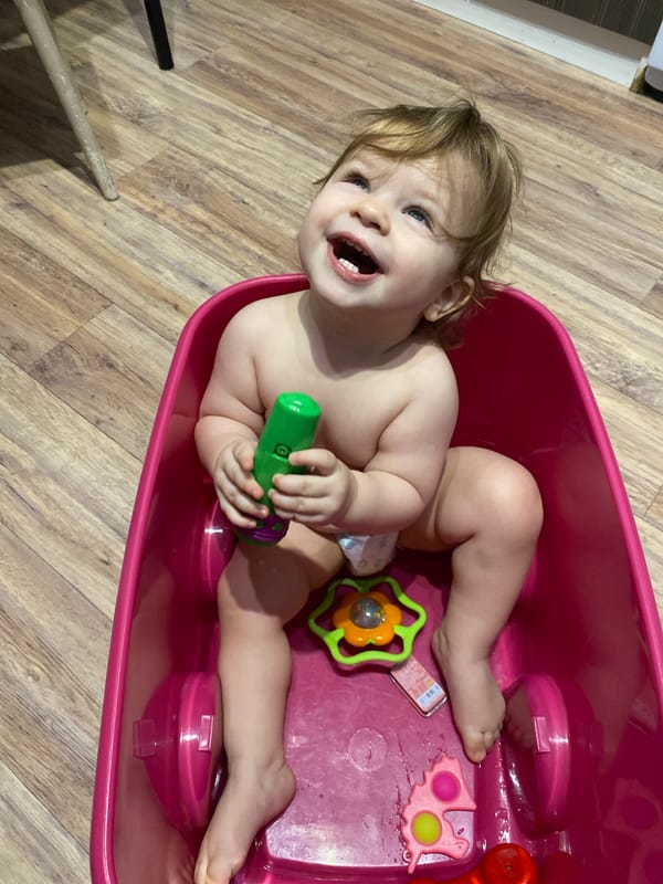 Toddler enjoys bath time with colorful toys