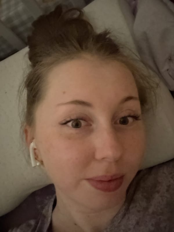 Person rests in bed with earbuds during evening hours