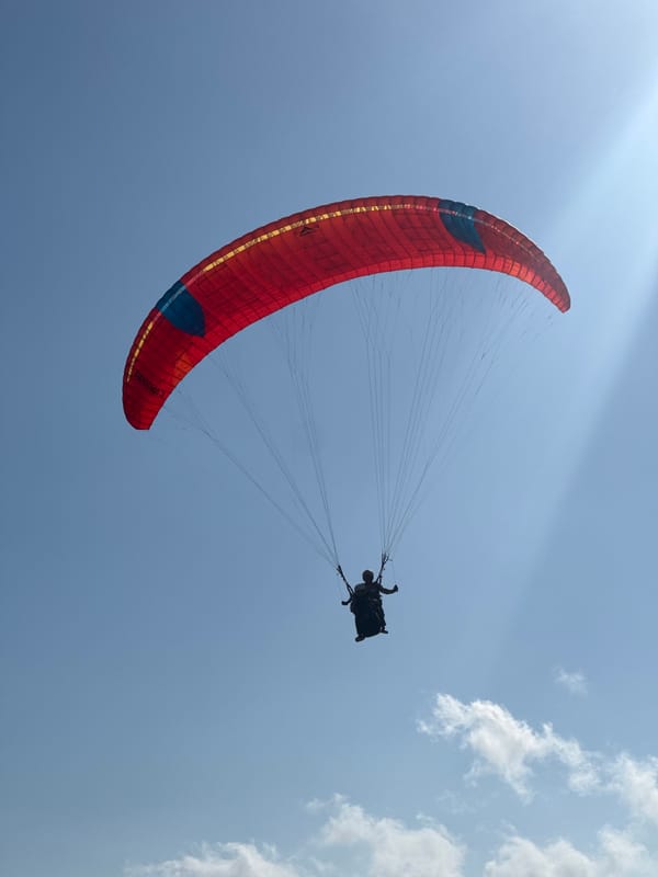 Paragliders swarm the Kuta Selatan coast on a clear morning