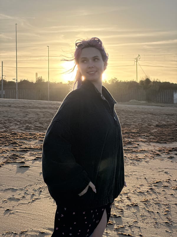 Purple-haired woman enjoys sunset beach walk with dog in Gijón