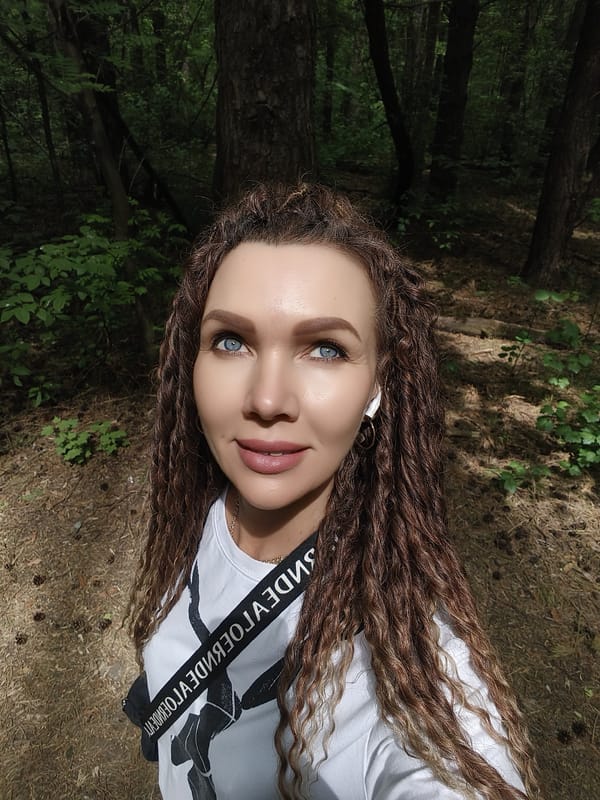 Woman photographing in forest, white shirt, earbuds observed