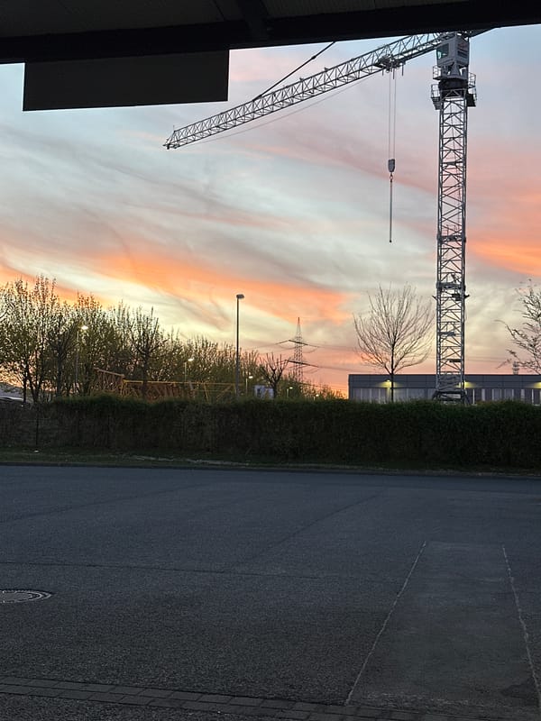Construction crane silhouetted against vibrant sunset in Frankfurt