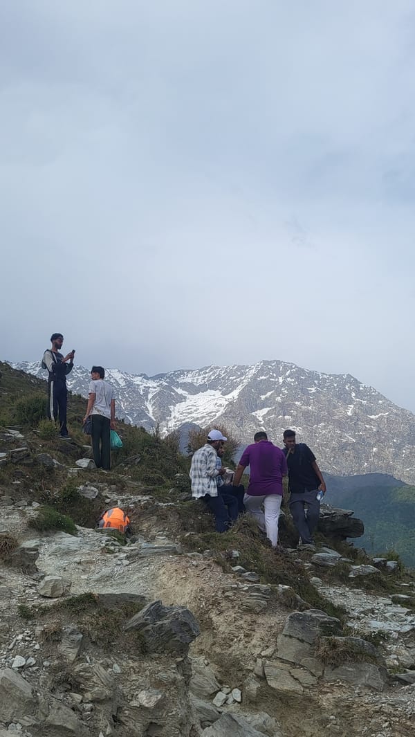 Hikers traverse rocky trail near Dharamshala amid overcast skies