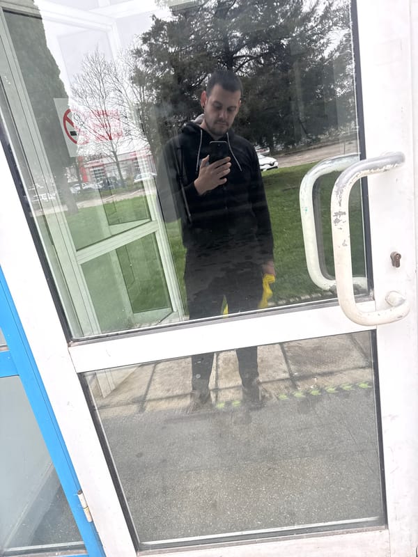 Man with phone reflected in glass door in Varna