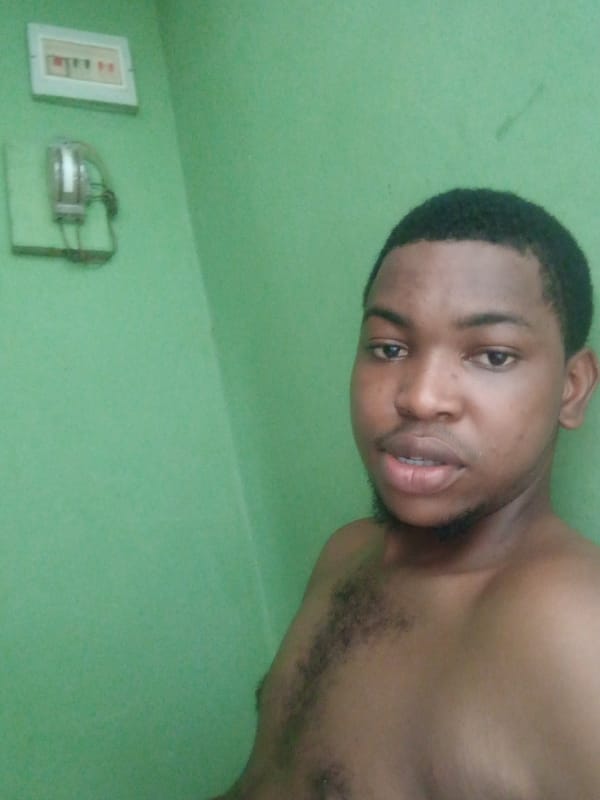 Portrait of shirtless man photographed against green wall