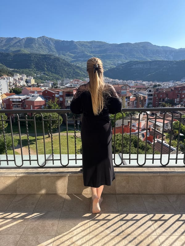 Woman in black dress observed on Budva balcony overlooking mountains