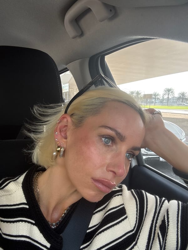 Woman in striped sweater sits in Dubai car listening to audio
