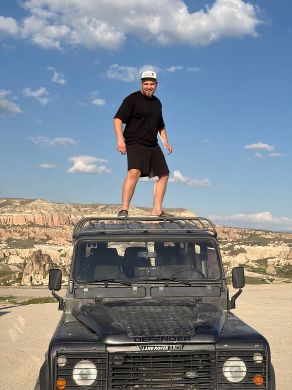 Man poses on Land Rover in Göreme's geological landscape