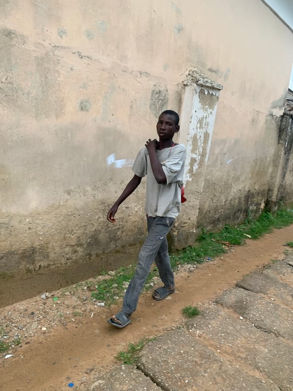 Morning foot traffic along a walled pathway in Abuja