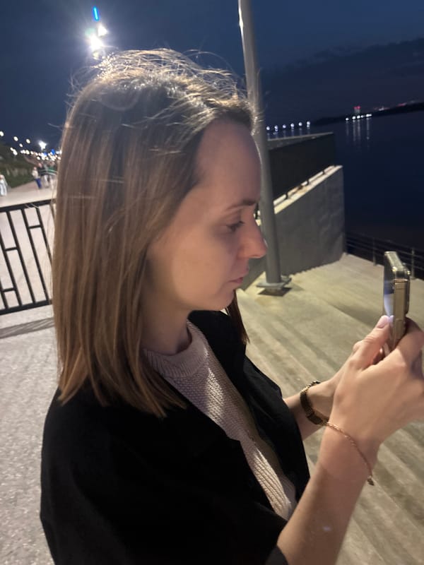Woman uses phone at Perm waterfront during evening hours