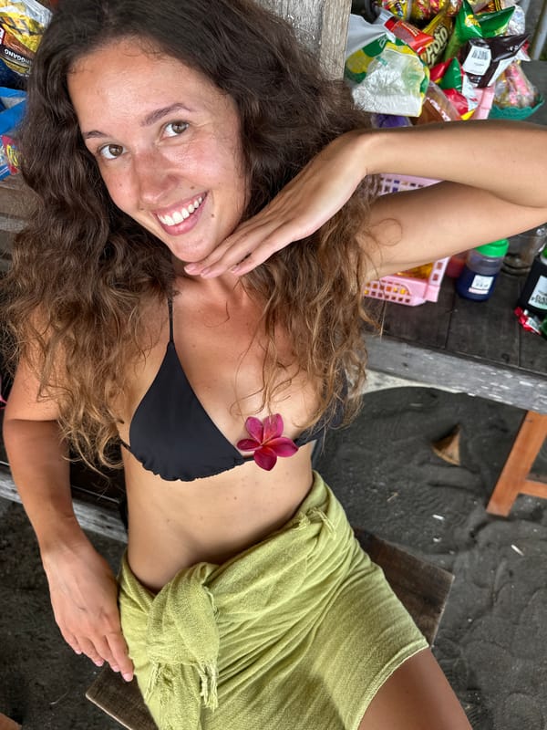 Woman rests with plumeria flowers on wooden surface in Pekutatan