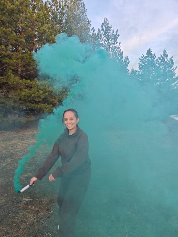 Woman poses with colored smoke grenades in Russian forest