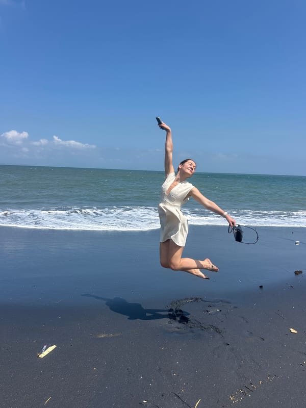 Jumping and posing on a black sand beach in Mengwi
