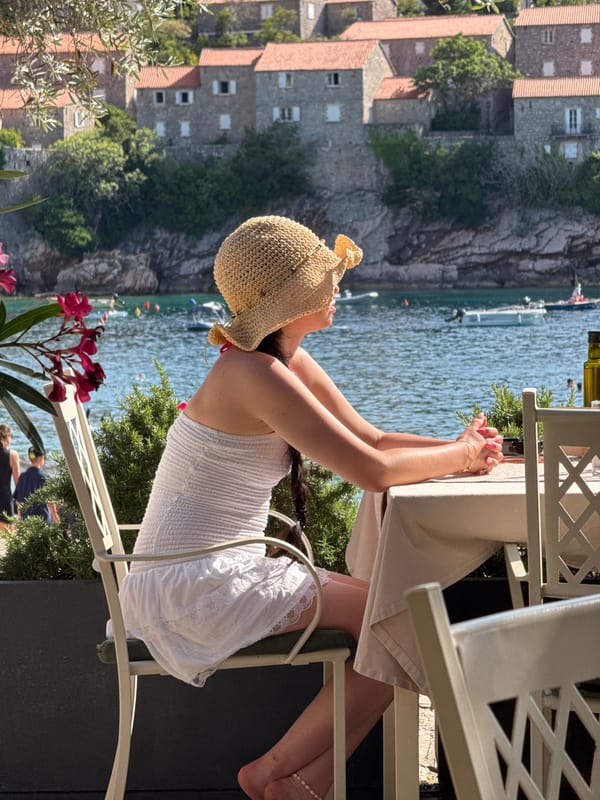 Woman dines at seaside restaurant overlooking Sveti Stefan, Montenegro