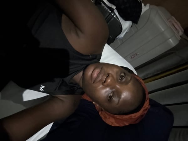 Woman in orange headwrap rests on bed in Nigeria