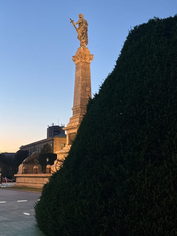 Sword-bearing monument outside a Cyrillic-inscribed civic building at dusk