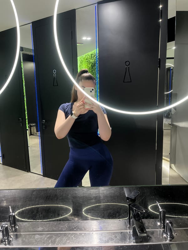 Woman takes selfies in dark mirrored indoor space