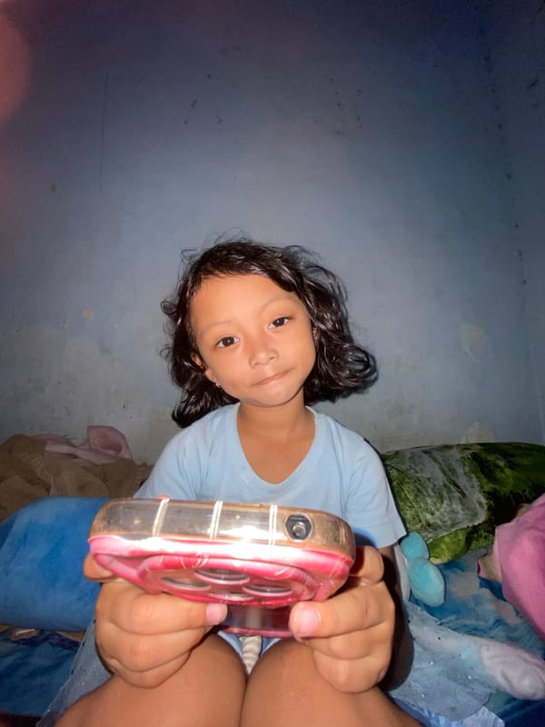Child displays toy object indoors in Gelam, Indonesia