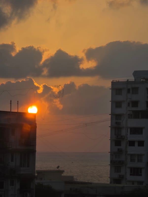 Sunset observed over Mumbai skyline with orange light through clouds