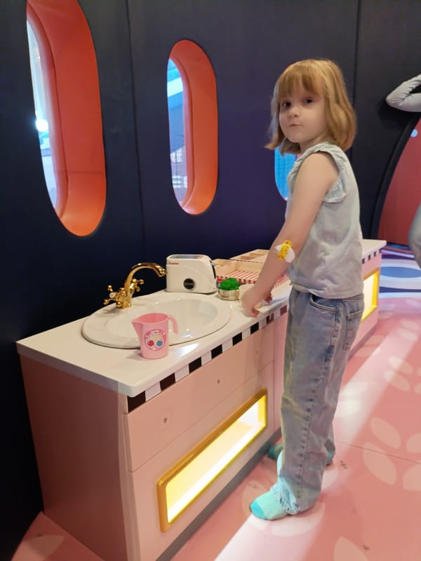 Girl with bandaged arm plays at toy kitchen